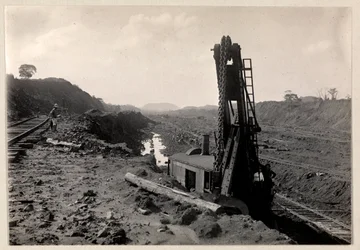 Vista dei lavoratori che scavano il Canale di Panama con binari ferroviari attraverso una trincea e una sorta di macchina scavatrice in primo piano, 1912 o 1913